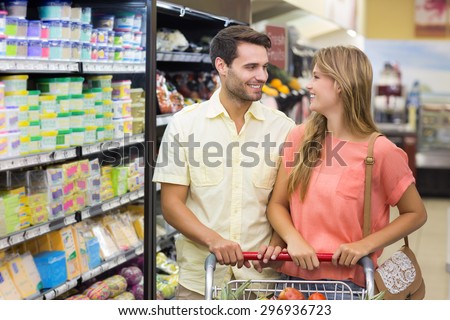 Smiling bright couple buying products at supermarket