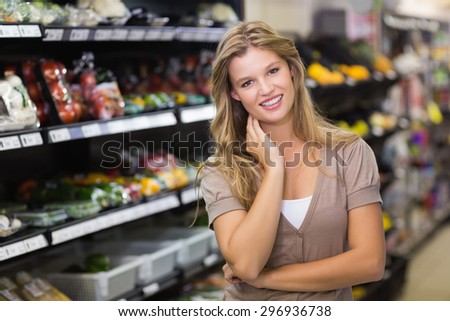 Portrait of a pretty blonde woman with hand on face at supermarket