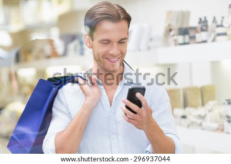 A happy smiling man looking at the phone at the mall
