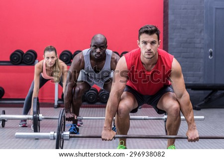 Portrait of three muscular athletes lifting barbells