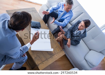 Angry business people speaking together on couch in office