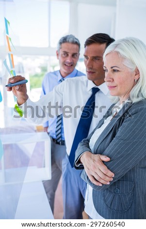 Businessman writing on post it with his colleagues in office