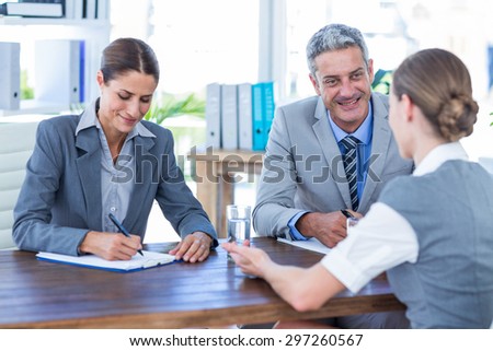 Business people interviewing young businesswoman in office