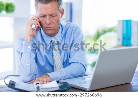 Serious businessman having phone call in office
