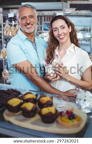 Cute couple looking at camera and standing arm around in the bakery store