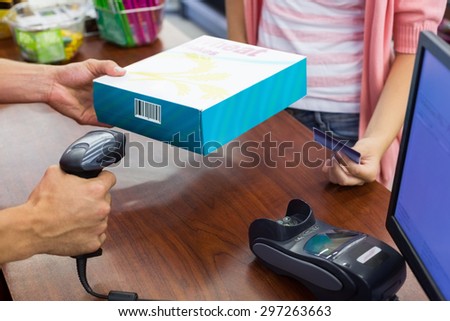 Smiling woman at cash register paying with credit card and scan a product in supermarket