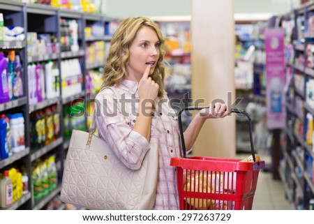 Side view of a pretty blonde woman having a shopping bag and looking ar shelf in supermarket