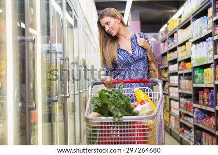 Woman buying products with his trolley at supermarket