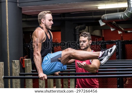 Trainer supervising a man doing exercises on parallel bar