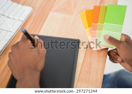 Young businessman writing on the graphic tablet at his desk in the office