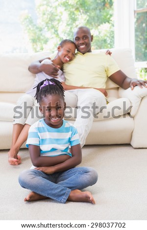 Portrait of a happy couple sitting on couch and their daughter sitting and looking at camera in the living room