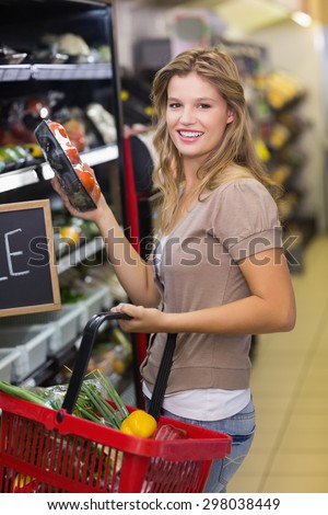 Portrait of smiling pretty blonde woman buying products at supermarket