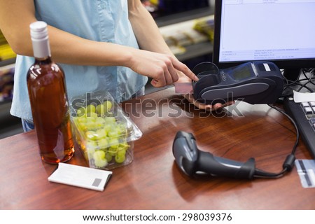 Woman at cash register paying with credit card in supermarket