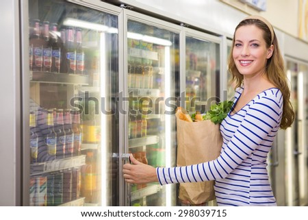 Pretty woman taking product on fridge at supermarket