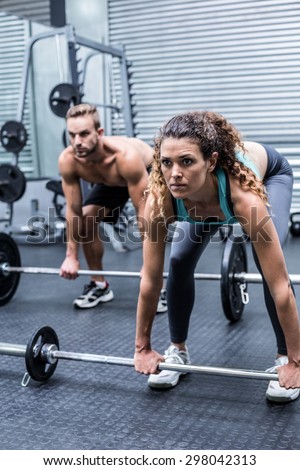 Side view of a muscular couple about to lift weights