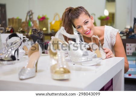 Portrait of smiling woman standing behind shoes at a shoe shop