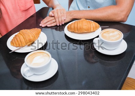 Coffee with hearts and bread with happy couple behind it in the cafe