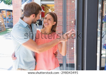 Young happy couple looking at a window of a clothing store