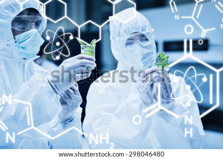 Science graphic against students in protective suits looking at plants in beakers