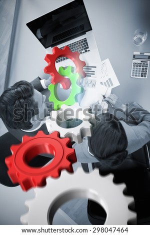 White and red cogs and wheels against sales persons studying statistics