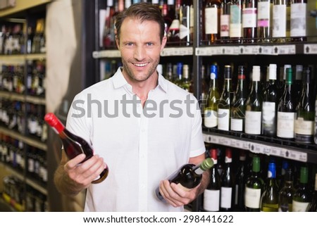 Portrait of a smiling handsome showing a wine bottle in supermarket