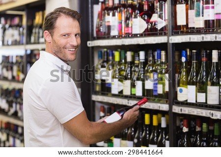 Portrait of a smiling handsome having a wine bottle in her hands in supermarket