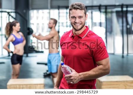 Portrait of muscular trainer with athletes on the background