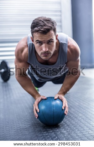 Portrait of a Muscular man on a plank position with a ball