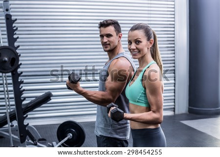 Portrait of a muscular couple lifting dumbbells