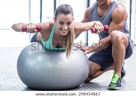 Portrait of a muscular woman balancing while lifting dumbbells