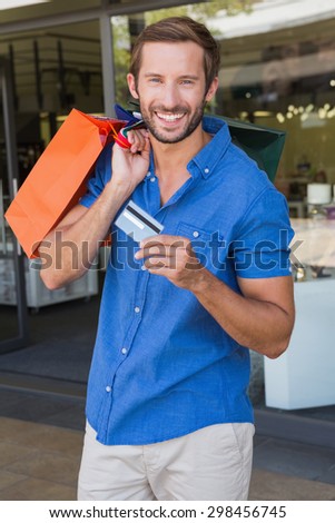 Young happy man holding shopping bags and a credit card after shopping