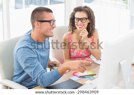Smiling colleagues pointing computer in the office