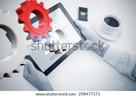 Man using tablet pc against white and red cogs and wheels