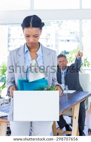 A fired businesswoman holding box in office
