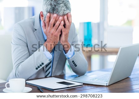 Depressed businessman with hands on head in office