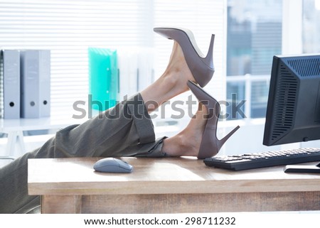 Businesswoman sitting on swivel chair with feet on desk at the office