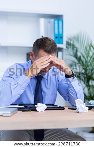 Elegant businessman with severe headache sitting at office desk
