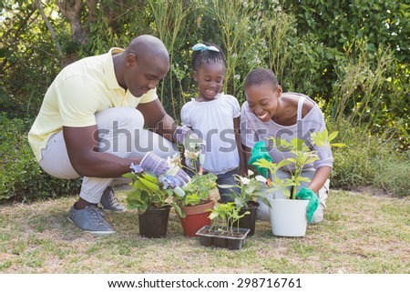 Happy smiling couple gardening with their daughter at home in garden