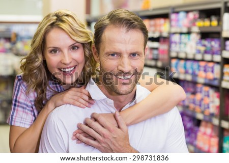 Portrait of smiling casual couple with arm around in supermarket