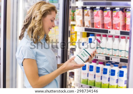 Smiling woman looking at a milk bottle in supermarket