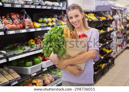 Pretty blonde holding bag with bread and vegetable in supermarket