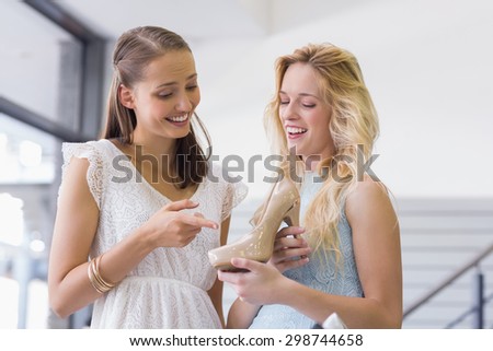 happy women talking and holding a heel shoe in shoe store