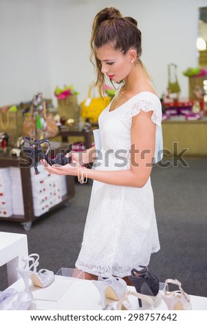 Smiling woman looking at high-heeled sandals at a shoe shop