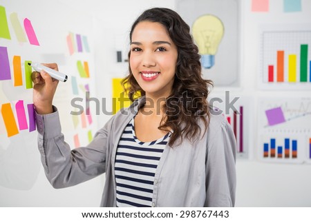 Young smiling creative businesswoman in the office writing on sticky notes