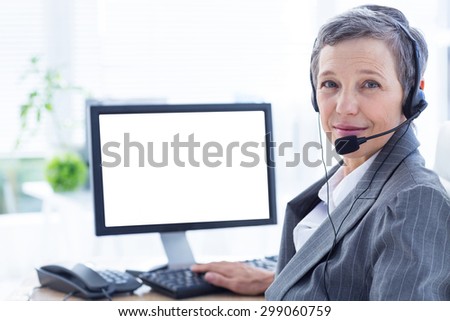 Smiling businesswoman phoning and using computer at the office