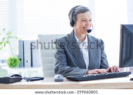 Smiling businesswoman using computer and phoning at the office