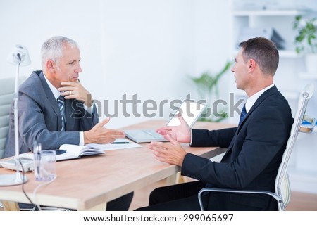Two serious businessmen speaking and working at the office