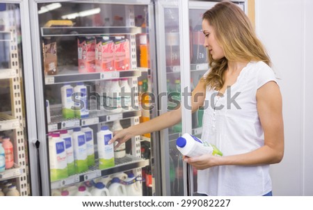 Pretty woman taking bottle of milk at supermarket