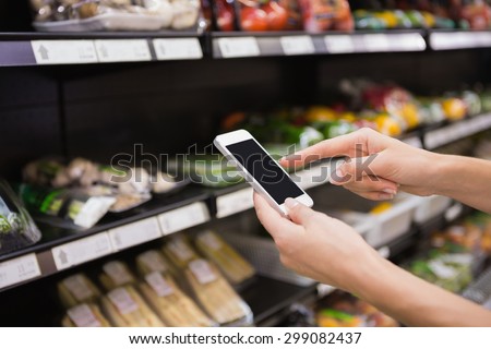 Woman buy products and using his smartphone at supermarket