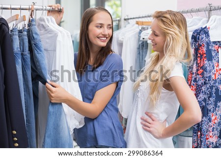 Enthusiastic friends browsing in the clothes rack